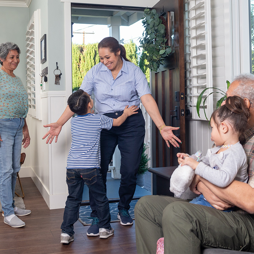 A mother and son hug in front of grandparents secure in retirement thanks to a registered index-linked annuity from TruStage™.