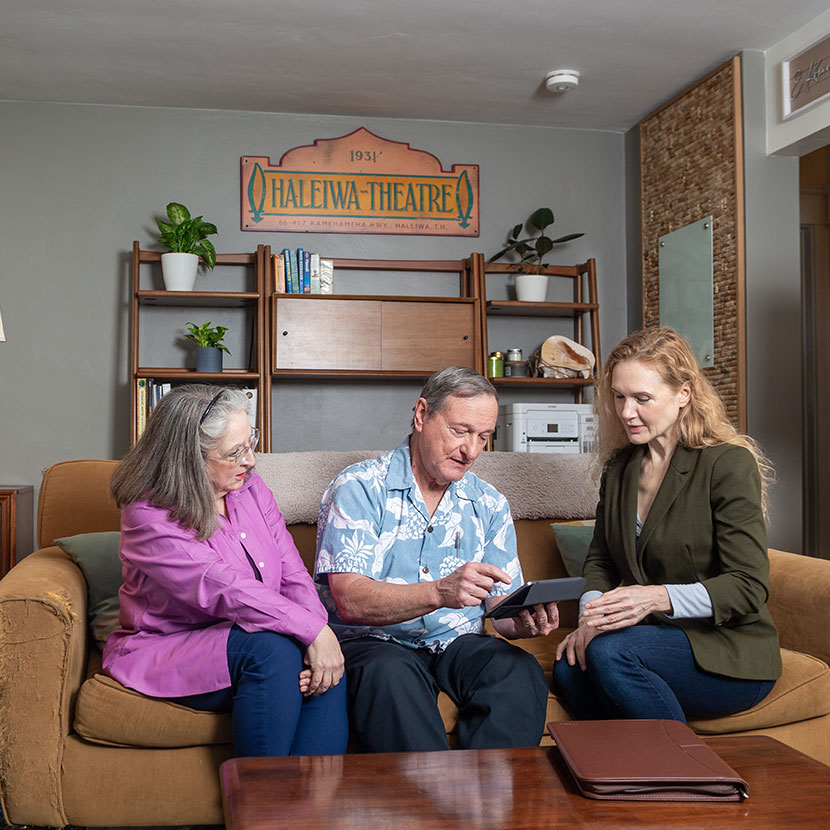 A man and woman sit on a couch with a financial professional and review a TruStage life insurance offer presented on a tablet.