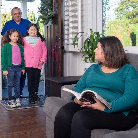 Two grandkids and grandpa greet grandma in her home protected by TruStage Insurance.