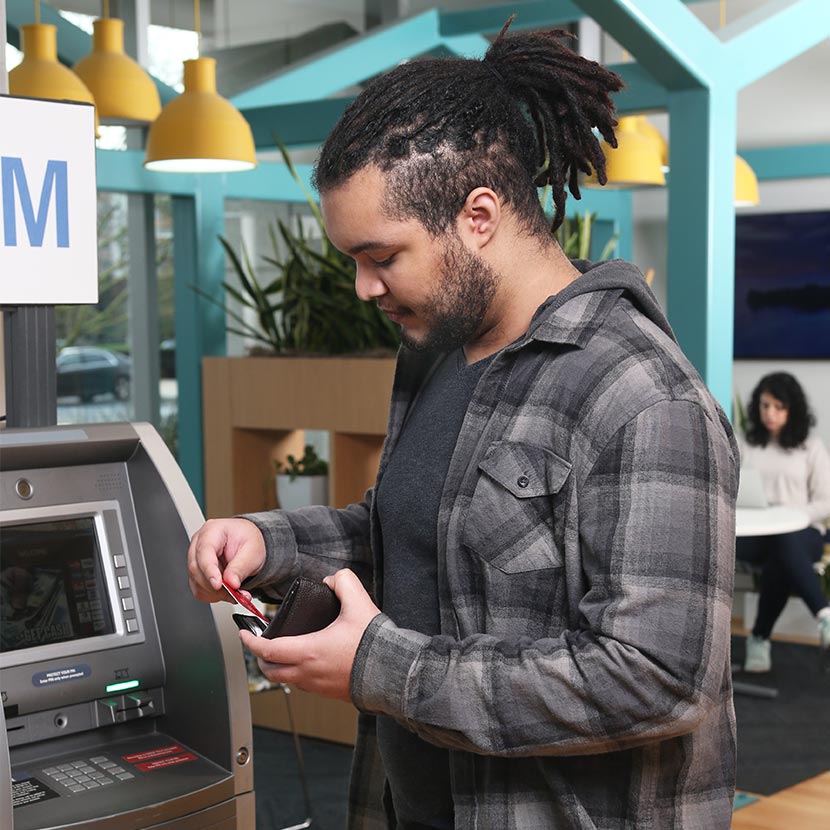 A man replaces his ATM card in his wallet after completing his transaction safely.