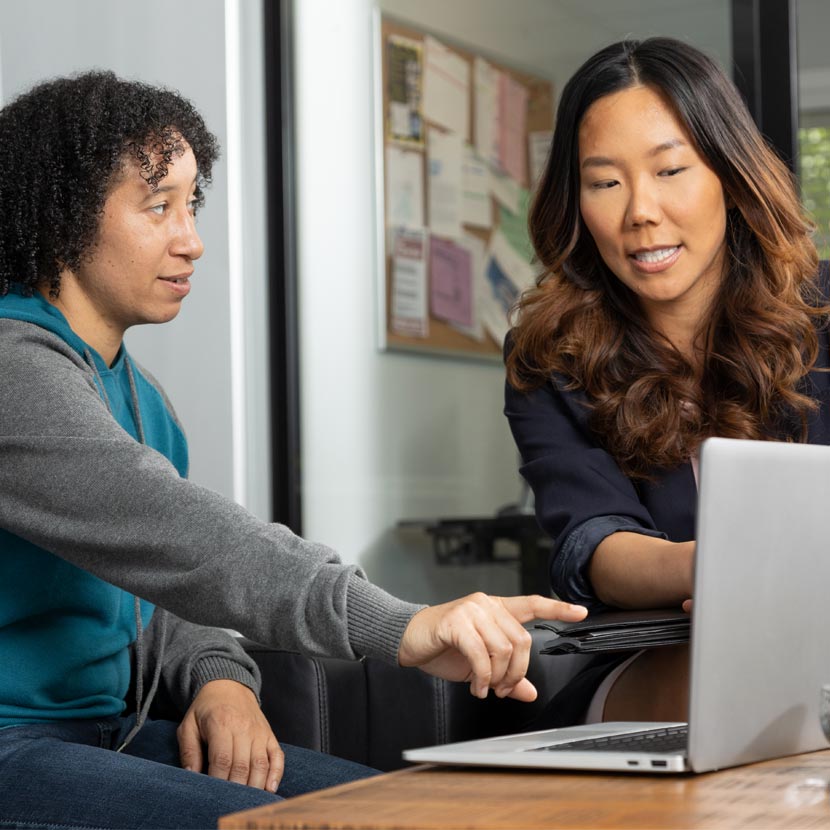 Two female employees review online fraudulent deposit training from TruStage.